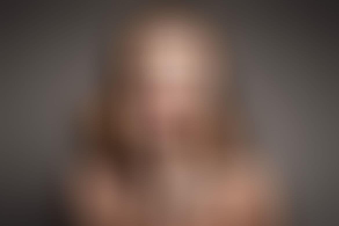 Retrato de una modelo con vestido de noche mirando a cámara en un estudio con luz cálida